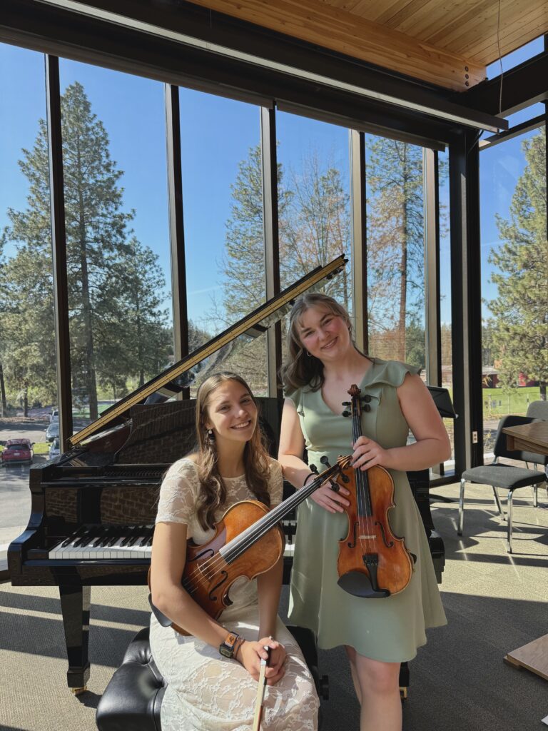 Samarah Heggestad and Bailie Jansons posing with their respective instruments, violin and viola.
